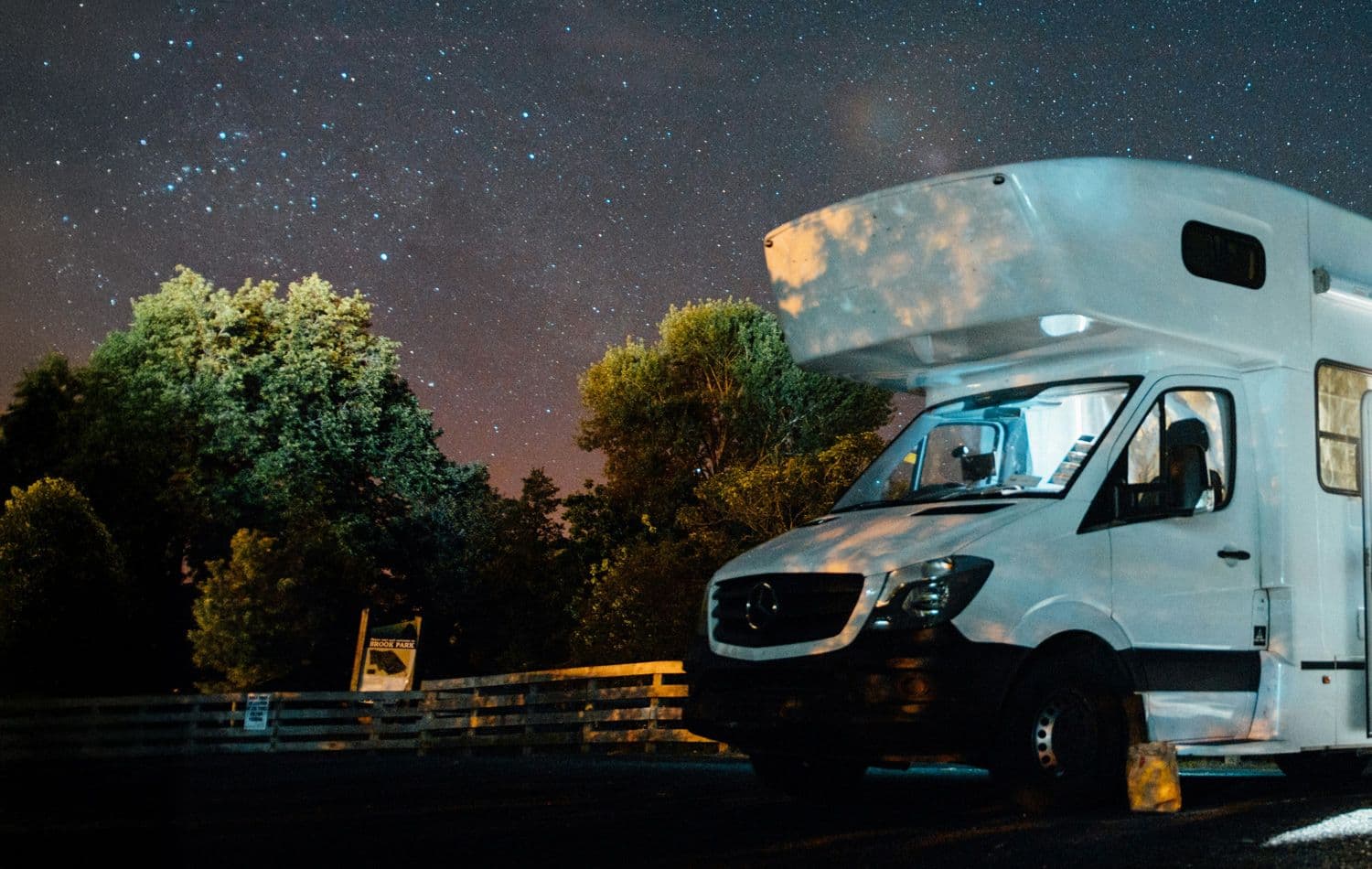 Un motorisé blanc garé la nuit, sous un ciel étoilé.